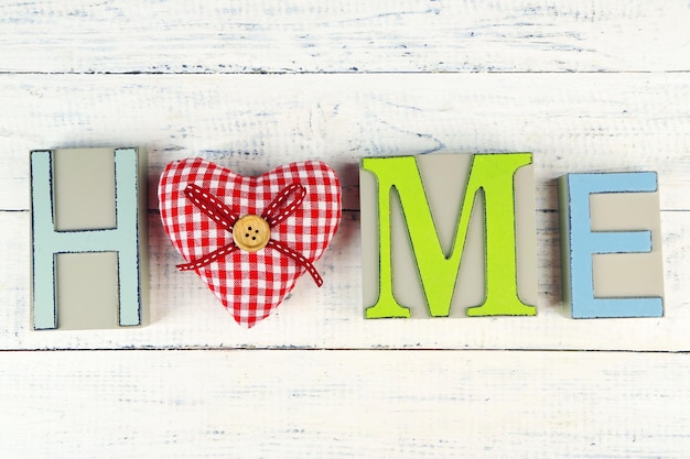 Lettere decorative che formano la parola HOME con cuore decorativo su sfondo di legno