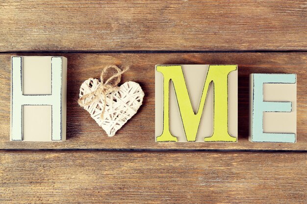 Lettere decorative che formano la parola HOME con cuore decorativo su sfondo di legno