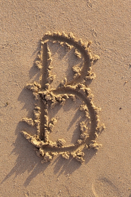 Lettere dell'alfabeto (B) scritte a mano nella sabbia sulla spiaggia