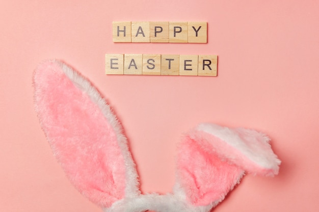 Lettere di BUONA PASQUA ed orecchie decorative del coniglietto isolate su fondo rosa