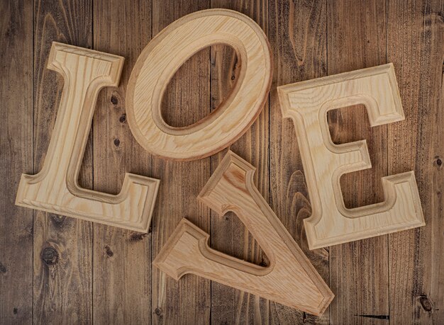 Lettere di legno disordinate che formano la parola amore su una tavola di legno di noce. Concetto di San Valentino
