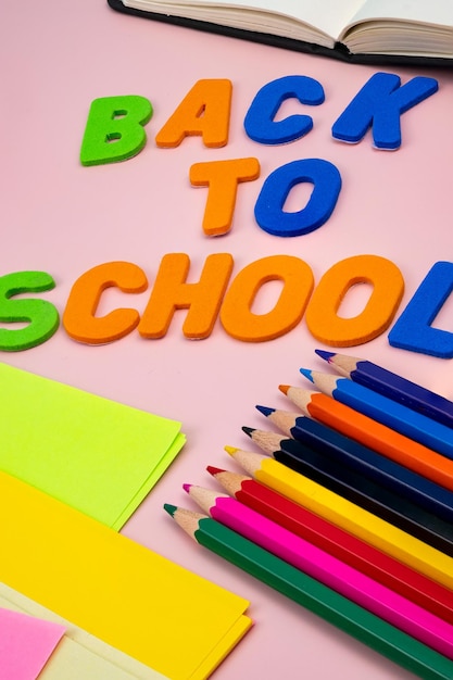 Lettere di ritorno a scuola, con materiale scolastico in cima a un tavolo rosa.