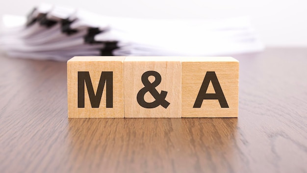 Lettere MA su cubi di blocchi di legno su tavolo di legno M e A Acronimi di fusioni e acquisizioni