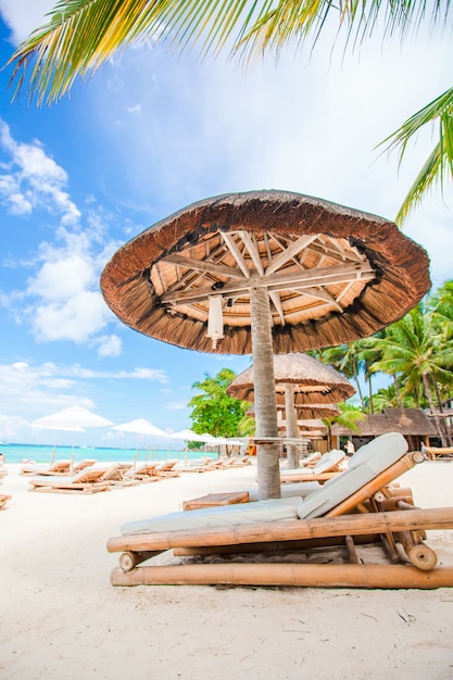 Lettini e ombrelloni sulla spiaggia di sabbia bianca tropicale esotica