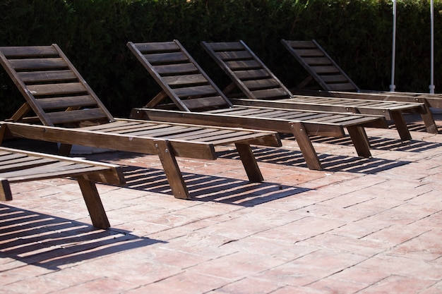 Lettini in legno vicino alla piscina. Senza persone.