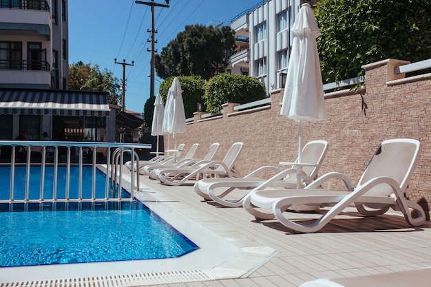 Lettini prendisole accanto alla piscina in hotel