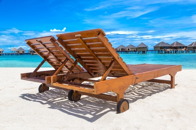 Lettino in legno sulla spiaggia tropicale delle Maldive