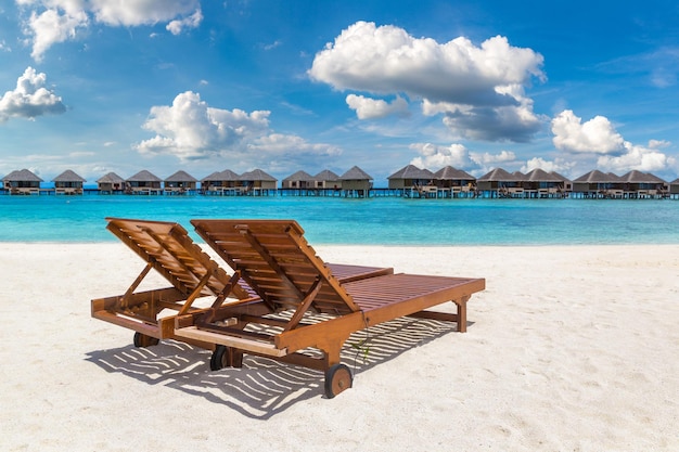 Lettino in legno sulla spiaggia tropicale delle Maldive