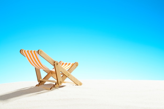 Lettino prendisole sulla spiaggia di sabbia, cielo con copia spazio