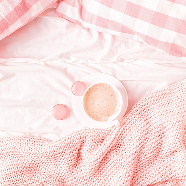 Letto con plaid in maglia rosa, caffè e amaretti