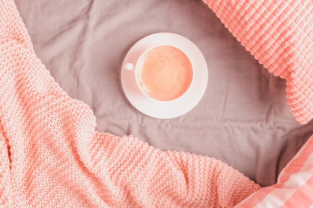 Letto con plaid lavorato a maglia rosa e caffè, vista dall'alto, spazio copia, laici piatta.