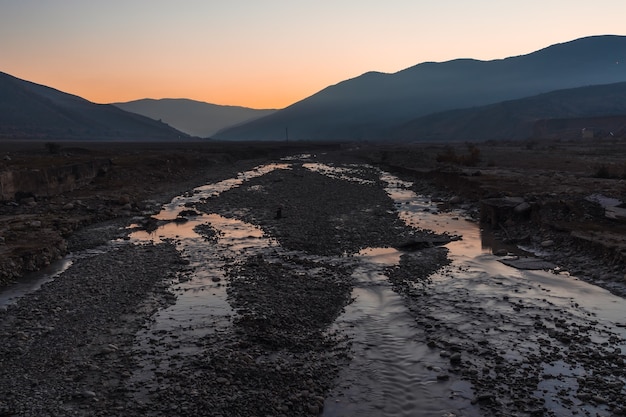 Letto del fiume di montagna al tramonto