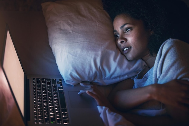 Letto portatile e donna su internet di notte per sito web online social media e relax a casa Computer da camera da letto e persona in streaming film e video su tecnologia pc con insonnia in casa