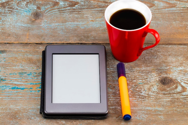 Lettore di e-book e tazza di caffè sul tavolo di legno.