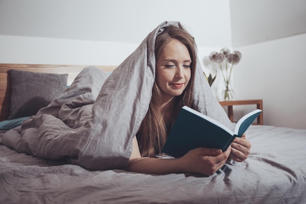 Lettura adorabile della donna che pone sul letto comodo