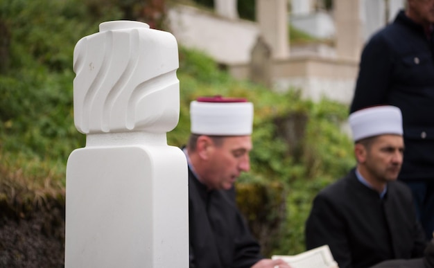 lettura del libro sacro del corano da parte dell'imam sul funerale islamico con il pollice bianco pietre sullo sfondo del graweyard
