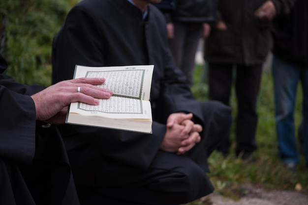 lettura del libro sacro del corano da parte dell'imam sul funerale islamico con il pollice bianco pietre sullo sfondo del graweyard