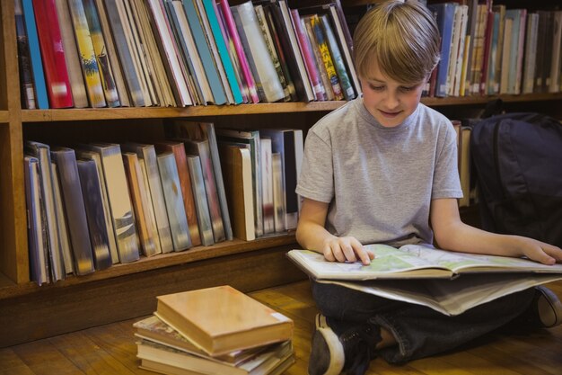 Lettura del ragazzino sul pavimento delle biblioteche