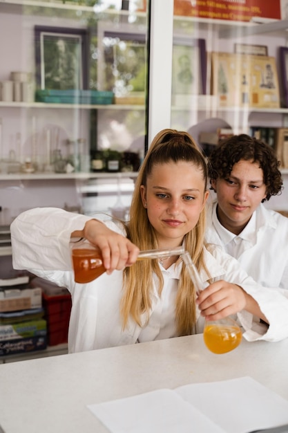 Lezione di chimica Studentessa e compagni di classe tengono la boccetta per esperimenti e sorrisi in laboratorio Istruzione scolastica