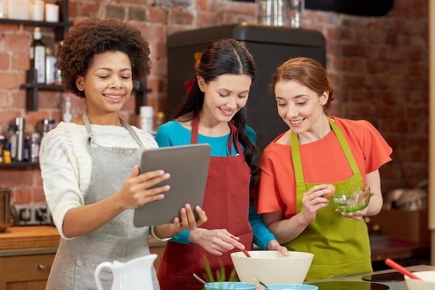 lezione di cucina, amicizia, cibo, tecnologia e concetto di persone - donne felici con computer tablet pc in cucina