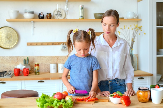 Lezione di cucina La mamma paziente felice insegna alla piccola figlia a cucinare cibi sani