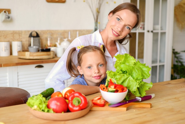 Lezione di cucina La mamma paziente felice insegna alla piccola figlia a cucinare cibi sani