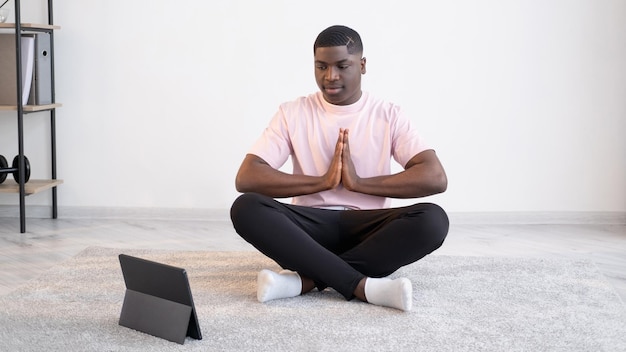 Lezione di pratica online per uomo di colore calmo a casa di yoga