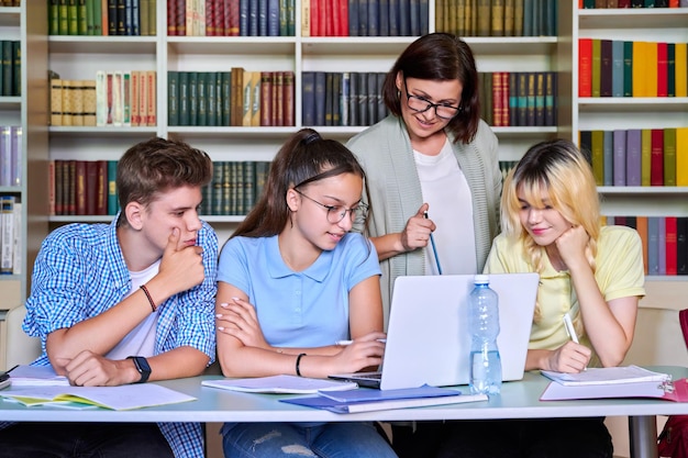 Lezione in biblioteca insegnante di scuola superiore con gruppo di adolescenti