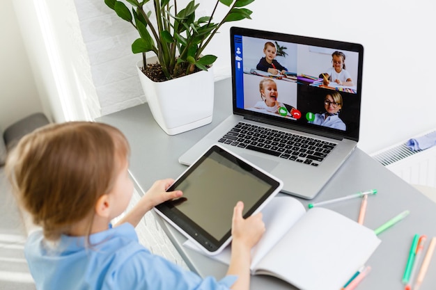 Lezioni a distanza. Il bambino sorride felice e acquisisce conoscenza a distanza. La bambina studia l'apprendimento online da casa. Scuola in linea.