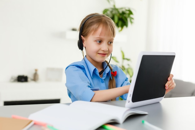 Lezioni a distanza. Il bambino sorride felice e acquisisce conoscenza a distanza. La bambina studia l'apprendimento online da casa. Scuola in linea.