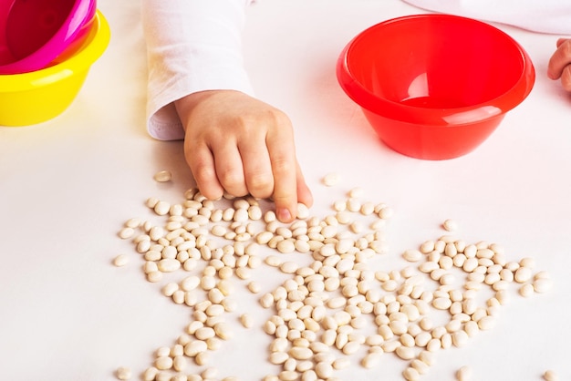 Lezioni di sviluppo per i bambini Lo sviluppo della motricità fine Fagioli e ciotola di plastica colorata Giocattoli naturali Asilo gioco di smistamento Scuola Montessori un sistema educativo