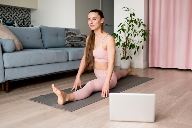 Lezioni di yoga online donna che fa yoga virtuale da laptop a casa per sviluppare la forza del nucleo