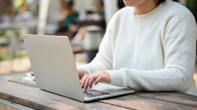 Libera professionista asiatica che lavora in remoto al suo progetto in un luogo all'aperto con un laptop