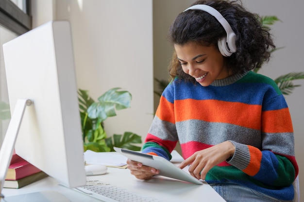 Libero professionista afroamericano sorridente che utilizza tablet digitale che lavora online da casa