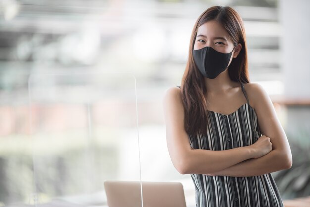Libero professionista asiatico donna d'affari che indossa maschera chirurgica, allontanamento sociale del nuovo stile di vita normale dopo l'epidemia di coronavirus COVID-19