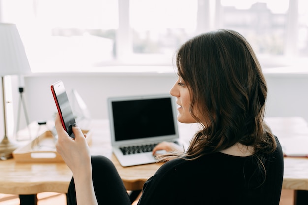 Libero professionista bruna giovane lavorando lavorando sul telefono