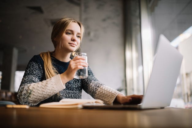 Libero professionista che utilizza computer portatile, digitando sulla tastiera, bevendo caffè in ufficio