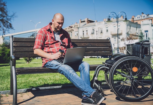Libero professionista con disabilità fisica che usa la sedia a rotelle che lavora nel parco
