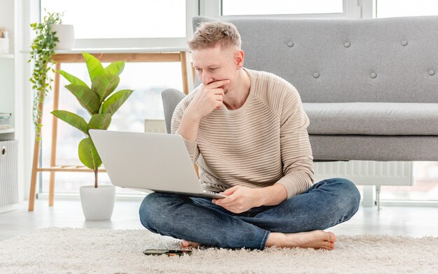 Libero professionista dell'uomo guardando il laptop e pensando durante l'orario di lavoro a distanza a casa