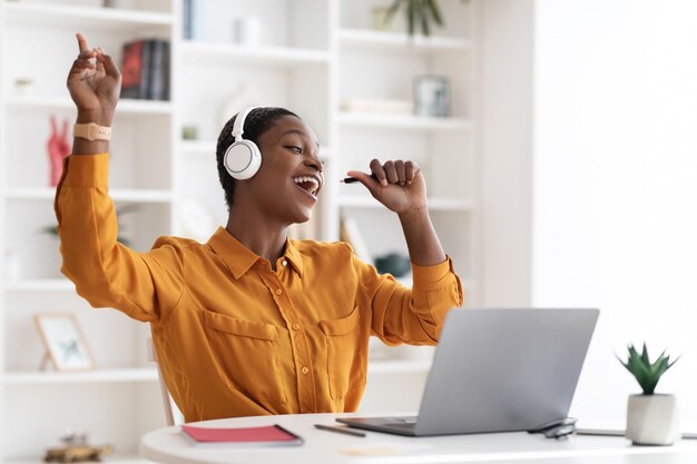 Libero professionista della donna afroamericana che canta il karaoke in ufficio