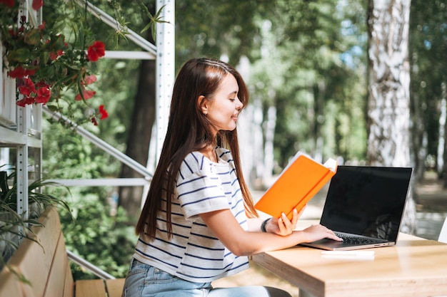 Libero professionista della giovane studentessa con capelli lunghi che lavora al computer portatile in caffè della via