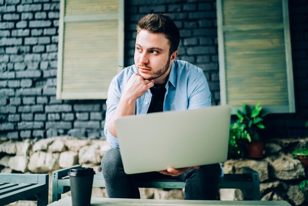 Libero professionista di pensiero che usa il laptop sulla terrazza