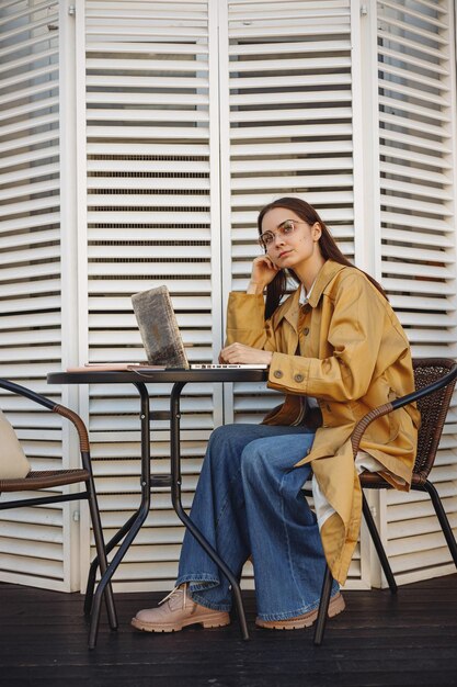 Libero professionista femminile premuroso che lavora al computer portatile nel caffè della città e pensa al progetto di affari