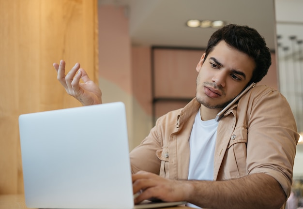 Libero professionista indiano che utilizza computer portatile, Internet, parlando sul telefono cellulare, comunicazione, lavoro da casa