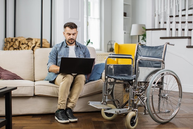 Libero professionista maschio con disabilità che digita su un computer portatile al chiuso