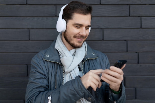 Libero professionista maschio europeo che ascolta musica in cuffia nell'app sul telefono