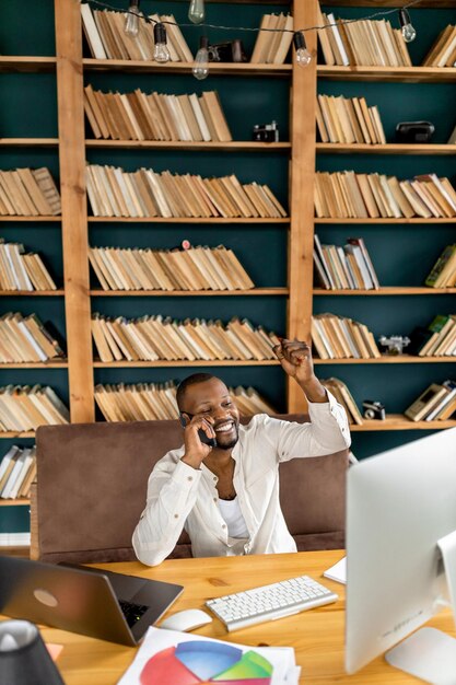 Libero professionista maschio gioioso che ha una riunione video di successo Sorridente maschio afroamericano che utilizza un computer portatile giallo che sta in cucina a casa concetto di lavoro a distanzaeccitato con buone notizie e successo aziendale