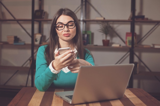 Libero professionista sta lavorando con qualcosa e seduto al tavolo con laptop e telefono