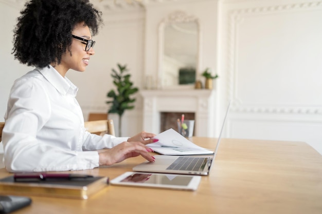 Libero professionista una donna con gli occhiali in ufficio che lavora a un progetto di avvio utilizzando un laptop