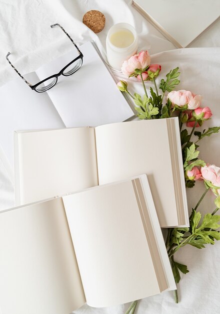 Libri, bicchieri e fiori aperti in bianco sul letto bianco, piatto disteso